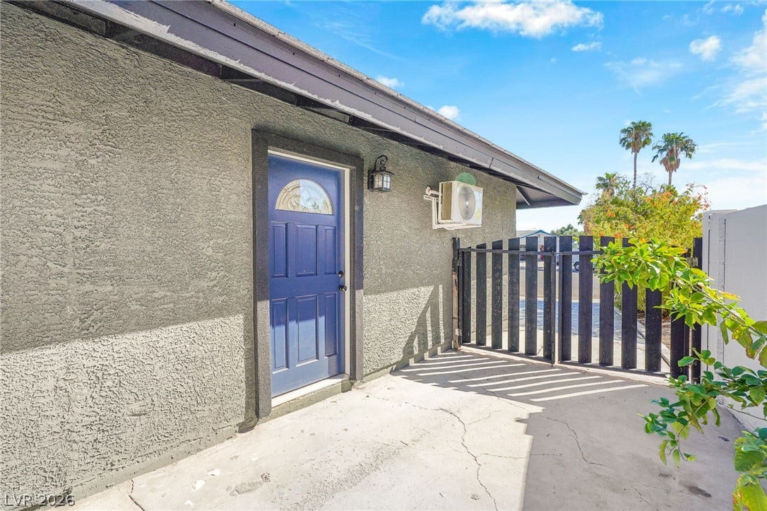 Stucco walls and a concrete entryway stand beside a secure gated access point.