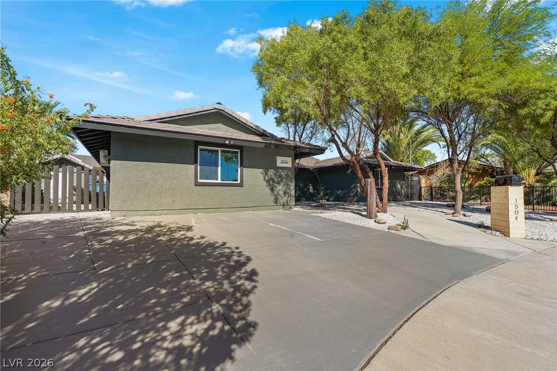 Mature trees shade the driveway and modern exterior finishes of this single-level home.