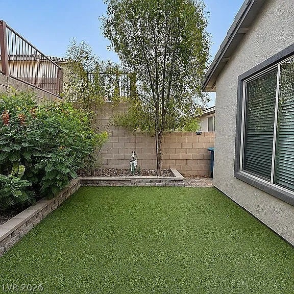 2126 Albury Avenue, North Las Vegas, NV 89086 An enclosed backyard space features artificial turf alongside tiered concrete block planter beds.