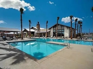 2126 Albury Avenue, North Las Vegas, NV 89086 Palm trees surround a pristine community swimming pool beside a modern clubhouse under sunny skies.
