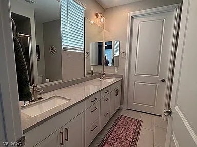 2126 Albury Avenue, North Las Vegas, NV 89086 Double vanities with stone counters flank a long, tile-floored bathroom layout.