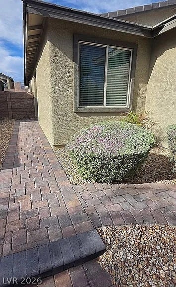 2126 Albury Avenue, North Las Vegas, NV 89086 Stone pavers line the side walkway of this stucco exterior house under blue skies.