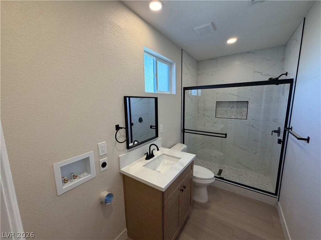 500 Grimsby Avenue, Henderson, NV 89014 A modern bathroom features a glass-enclosed walk-in shower with tile walls and a vanity with stone counter.