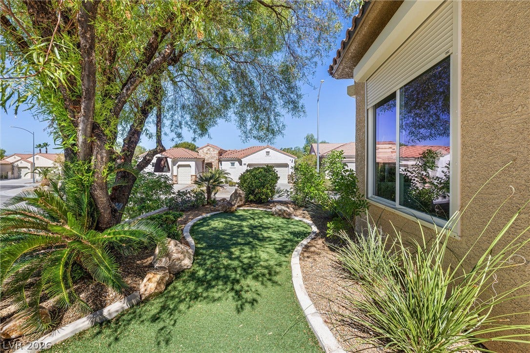 2107 Noah Tyler Ct., Henderson, NV 89052 Mature shade trees and manicured desert plantings flank a curved pathway near the stucco exterior.