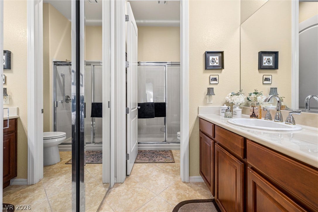 2107 Noah Tyler Ct., Henderson, NV 89052 Gleaming tile floors run throughout this bathroom featuring a wooden vanity and walk-in shower.