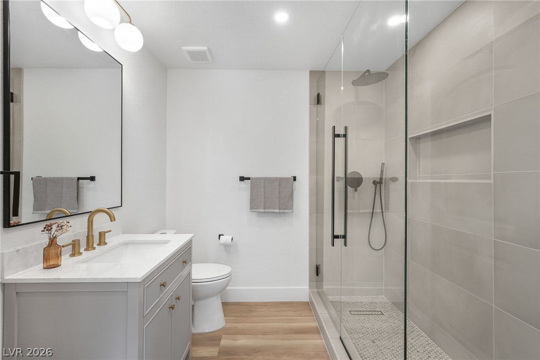 1287 Lime Point Street, Las Vegas, NV 89110 A glass-enclosed shower highlights this modern bathroom with a single vanity and warm wood flooring.