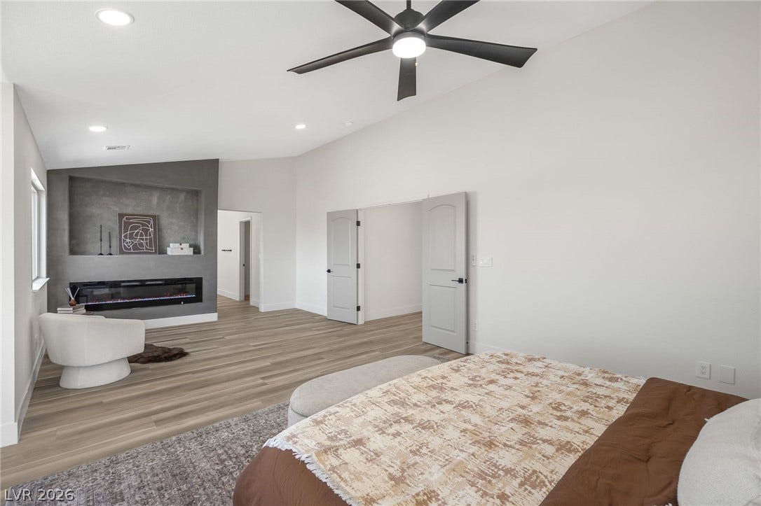 1287 Lime Point Street, Las Vegas, NV 89110 A modern fireplace highlights this spacious bedroom complete with vaulted ceilings and wood-style flooring.