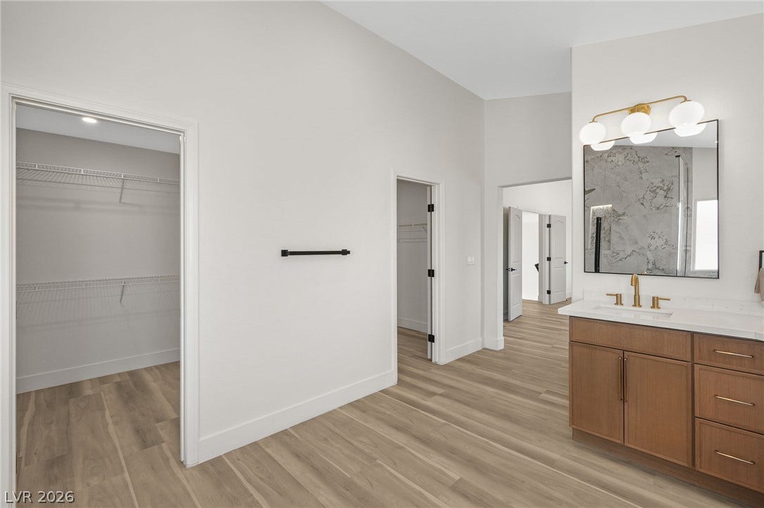 1287 Lime Point Street, Las Vegas, NV 89110 A spacious master bathroom vanity connects seamlessly to generous walk-in closet space and wood-style flooring.