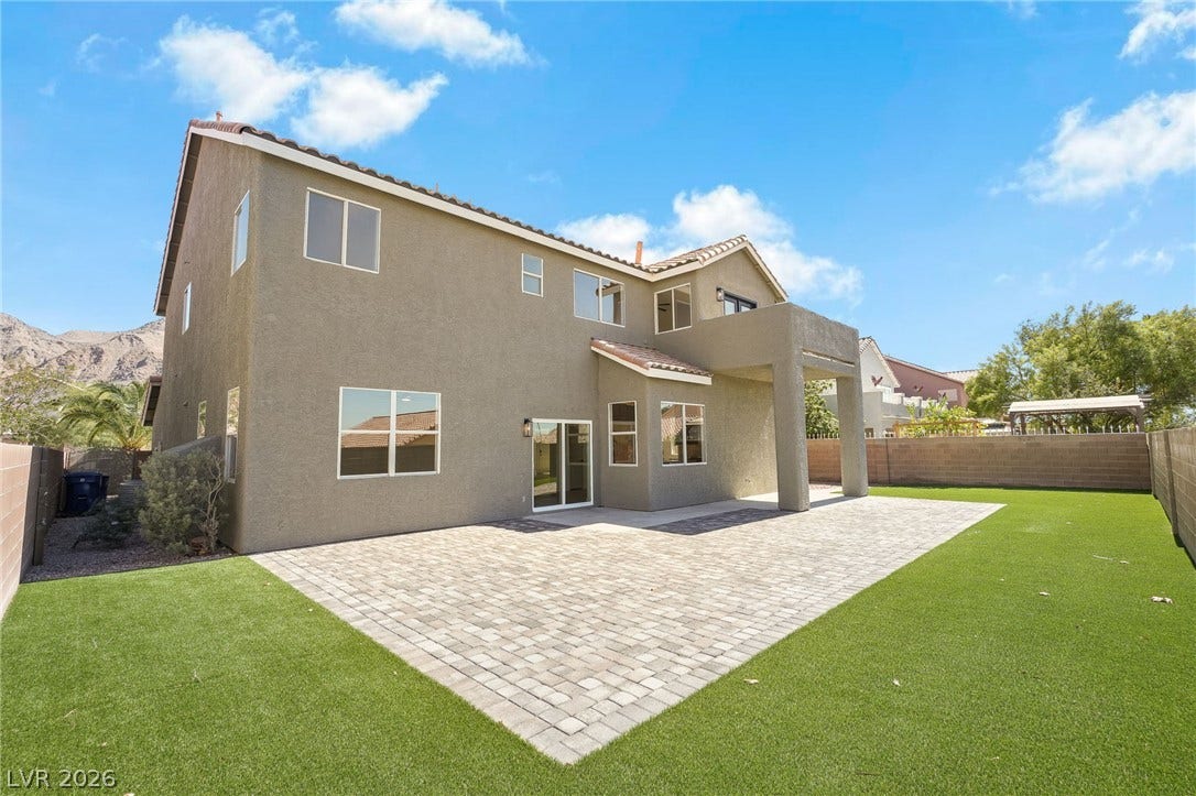1287 Lime Point Street, Las Vegas, NV 89110 A spacious backyard features structured paver decking alongside a neat lawn and mountain backdrops.