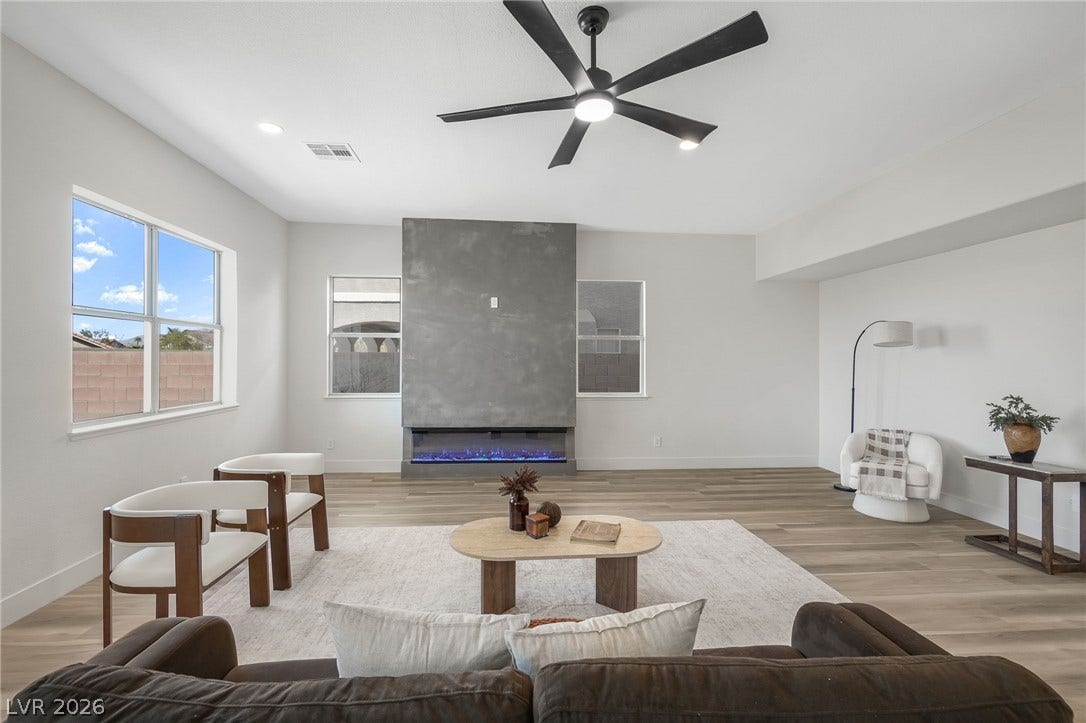 1287 Lime Point Street, Las Vegas, NV 89110 An impressive floor-to-ceiling fireplace anchors this modern living room with wood flooring.