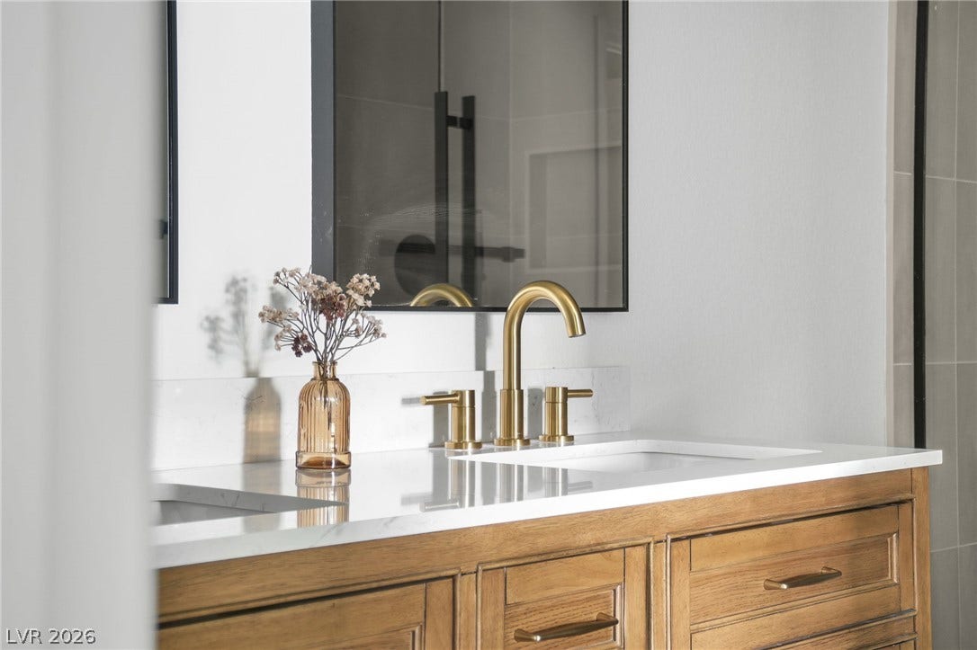 1287 Lime Point Street, Las Vegas, NV 89110 Elegant brass fixtures accent a double vanity topped with polished stone countertops.