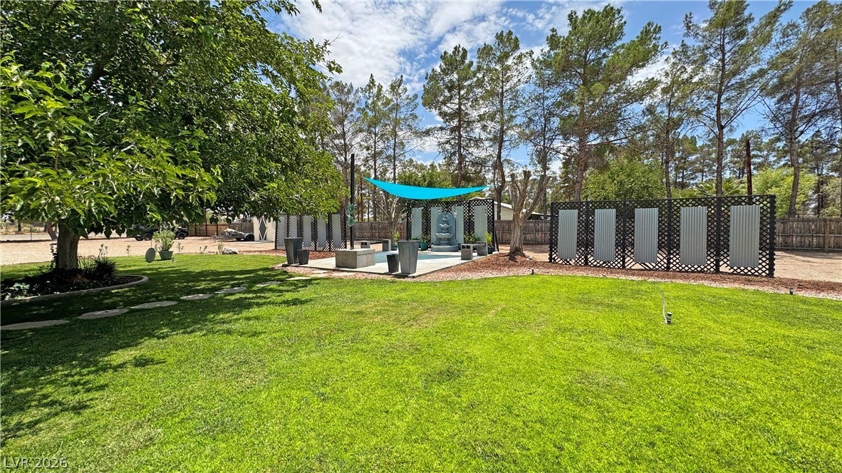 6130 Hawkins Way, Pahrump, NV 89061 Mature trees frame a manicured lawn leading to a paved patio area.