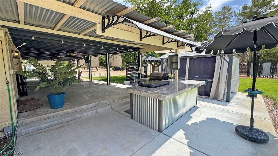 6130 Hawkins Way, Pahrump, NV 89061 An expansive covered concrete patio transitions seamlessly to a built-in outdoor kitchen and open yard.
