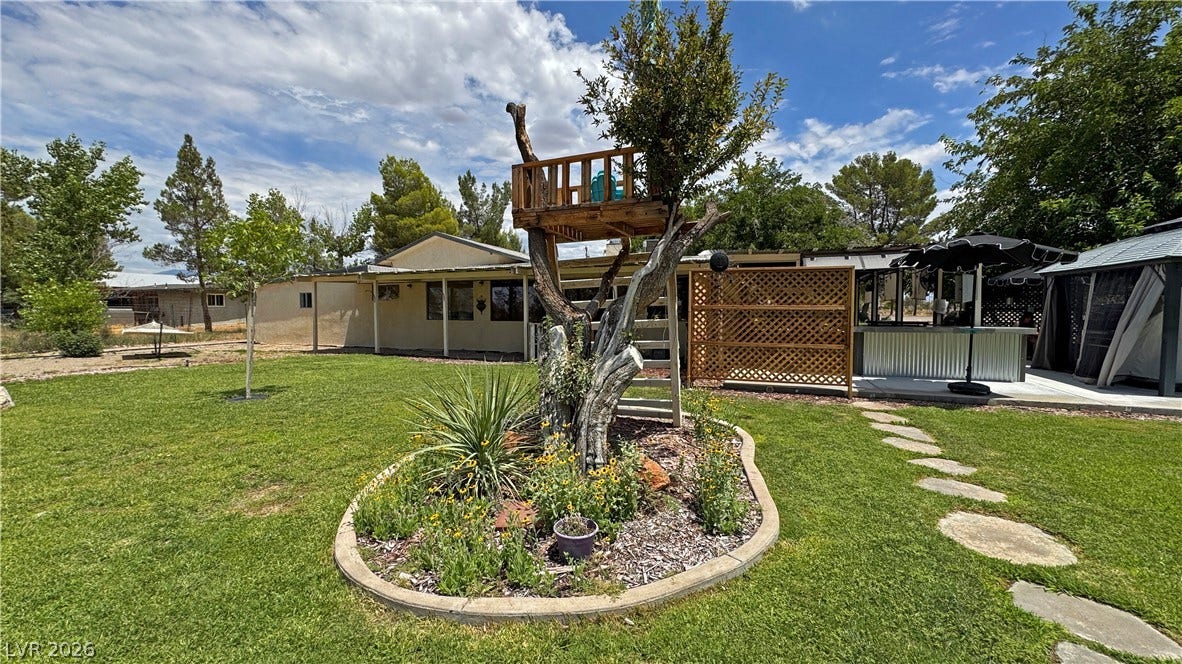 6130 Hawkins Way, Pahrump, NV 89061 Lush green grass and a charming treehouse define this spacious backyard setting.