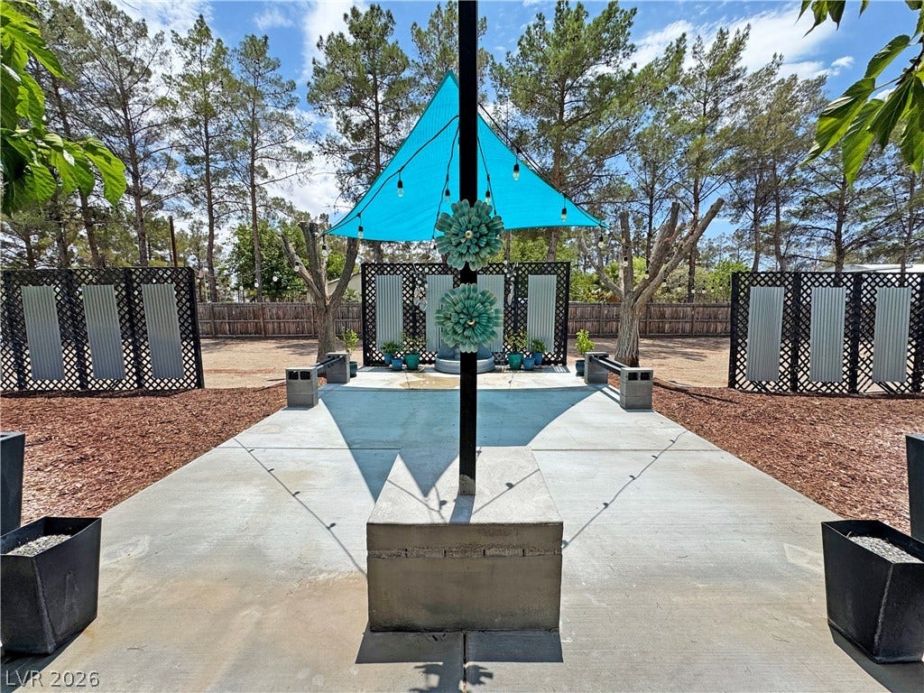 6130 Hawkins Way, Pahrump, NV 89061 Mature trees frame a concrete patio area featuring integrated privacy screens.