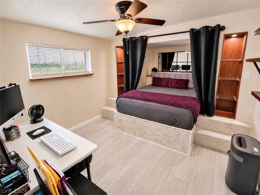 6130 Hawkins Way, Pahrump, NV 89061 A clever elevated bed platform sits opposite a workspace over wood-look flooring.