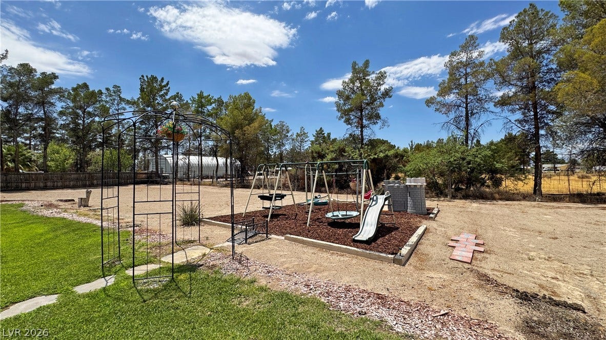 6130 Hawkins Way, Pahrump, NV 89061 Mature trees frame a spacious outdoor play area surrounded by natural landscape.