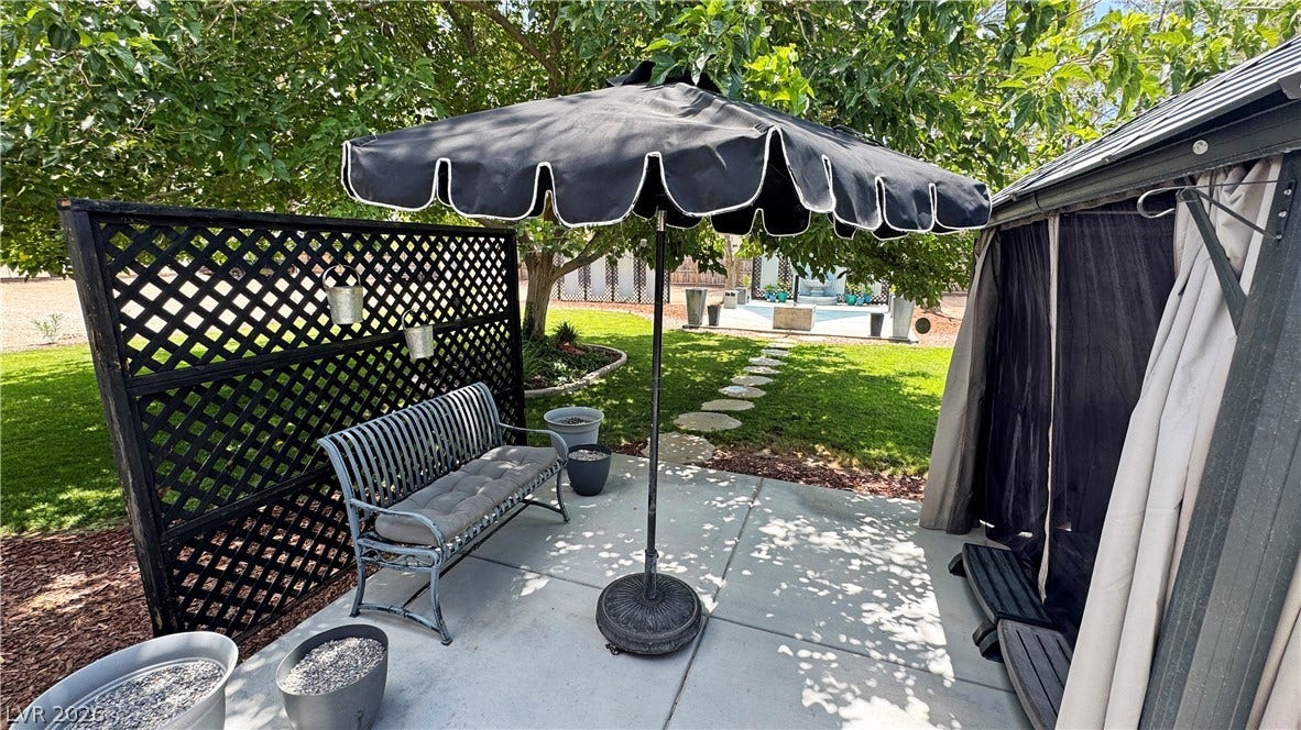 6130 Hawkins Way, Pahrump, NV 89061 Concrete patio tiles connect this quiet outdoor seating nook to the expansive grassy backyard.