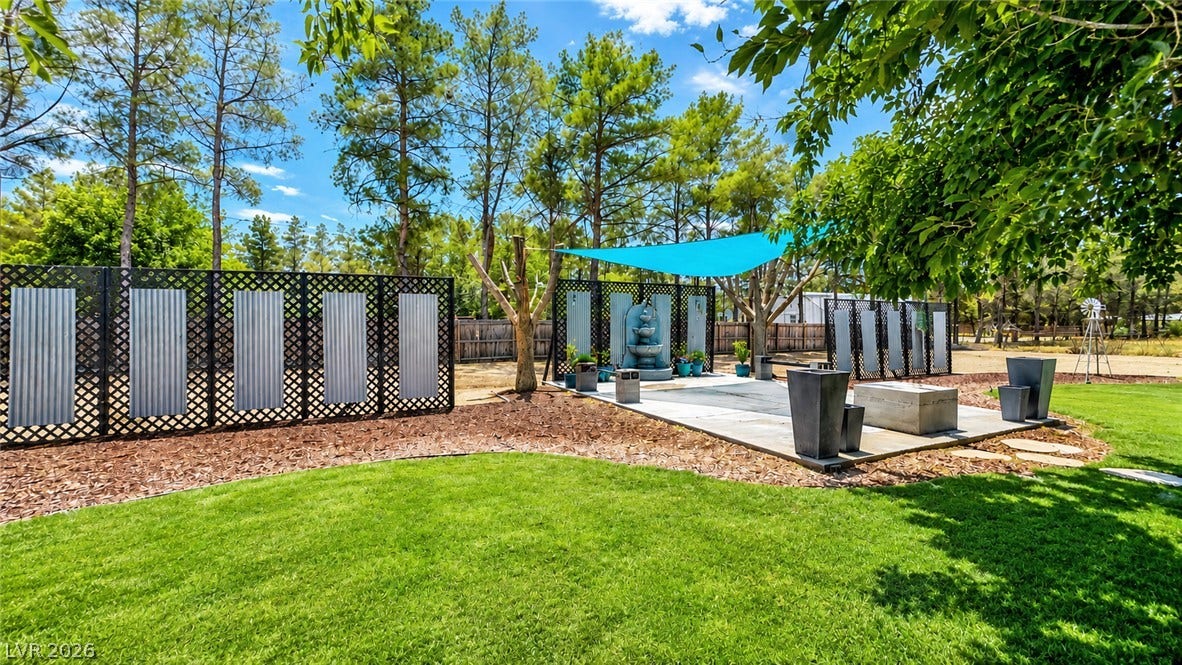 6130 Hawkins Way, Pahrump, NV 89061 Lush green grass and towering pine trees frame a peaceful outdoor patio retreat.