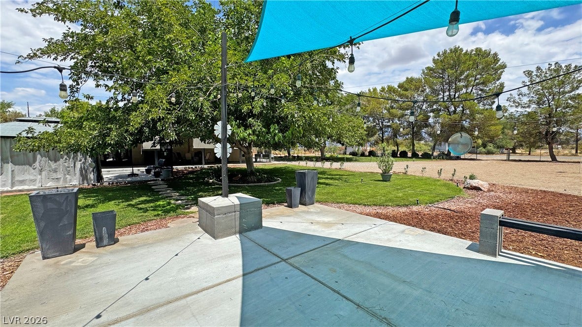 6130 Hawkins Way, Pahrump, NV 89061 A spacious concrete patio overlooks a grassy lawn bordered by mature shade trees.