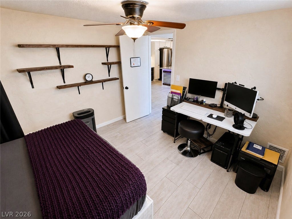 6130 Hawkins Way, Pahrump, NV 89061 A functional home office setup occupies a versatile bedroom space with textured walls and tile flooring.
