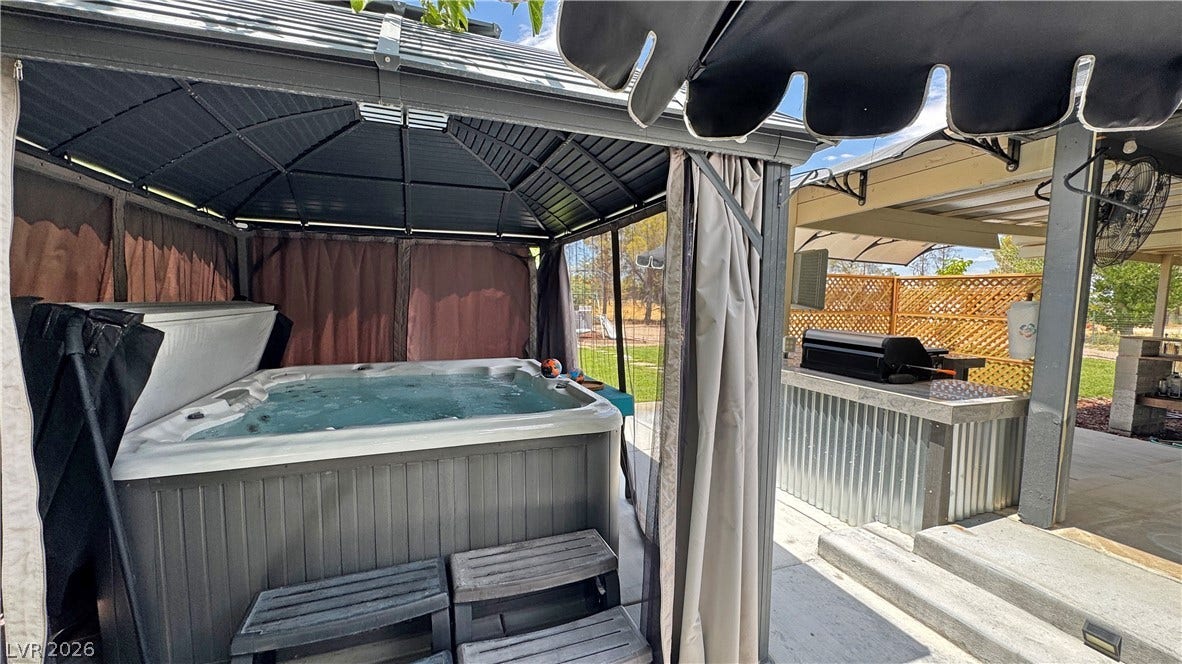 6130 Hawkins Way, Pahrump, NV 89061 An inviting covered patio features a hot tub, outdoor kitchen, and durable concrete steps.