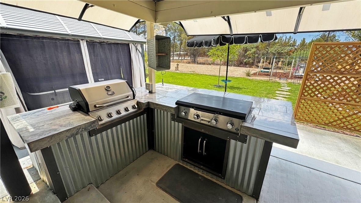 6130 Hawkins Way, Pahrump, NV 89061 An outdoor kitchen features durable stone countertops alongside built-in grilling stations overlooking the yard.