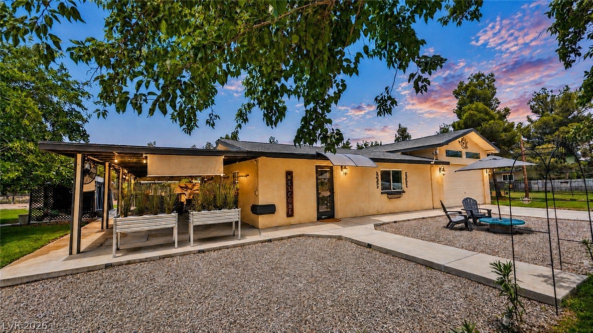 6130 Hawkins Way, Pahrump, NV 89061 A spacious concrete patio area transitions into gravel landscaping under a dramatic sunset sky.