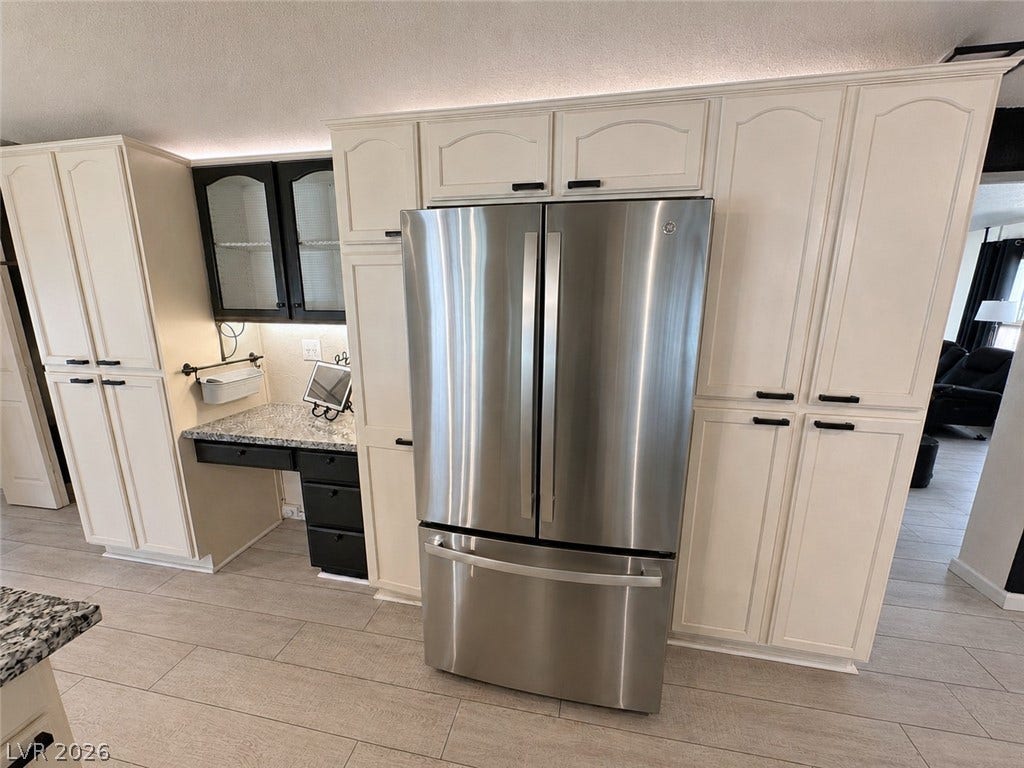 6130 Hawkins Way, Pahrump, NV 89061 Abundant built-in cabinetry and stone countertops frame a modern stainless steel refrigerator.