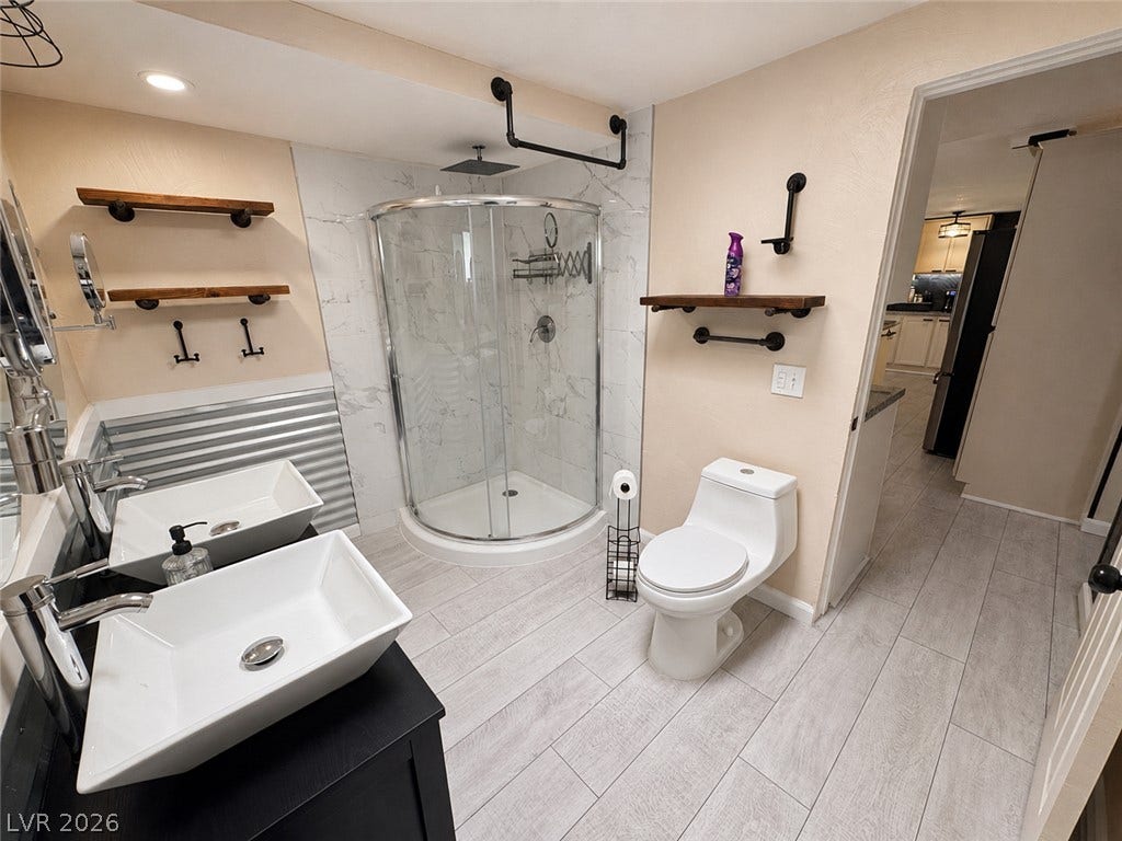 6130 Hawkins Way, Pahrump, NV 89061 Sleek tile flooring and dual vessel sinks define this contemporary bathroom space.