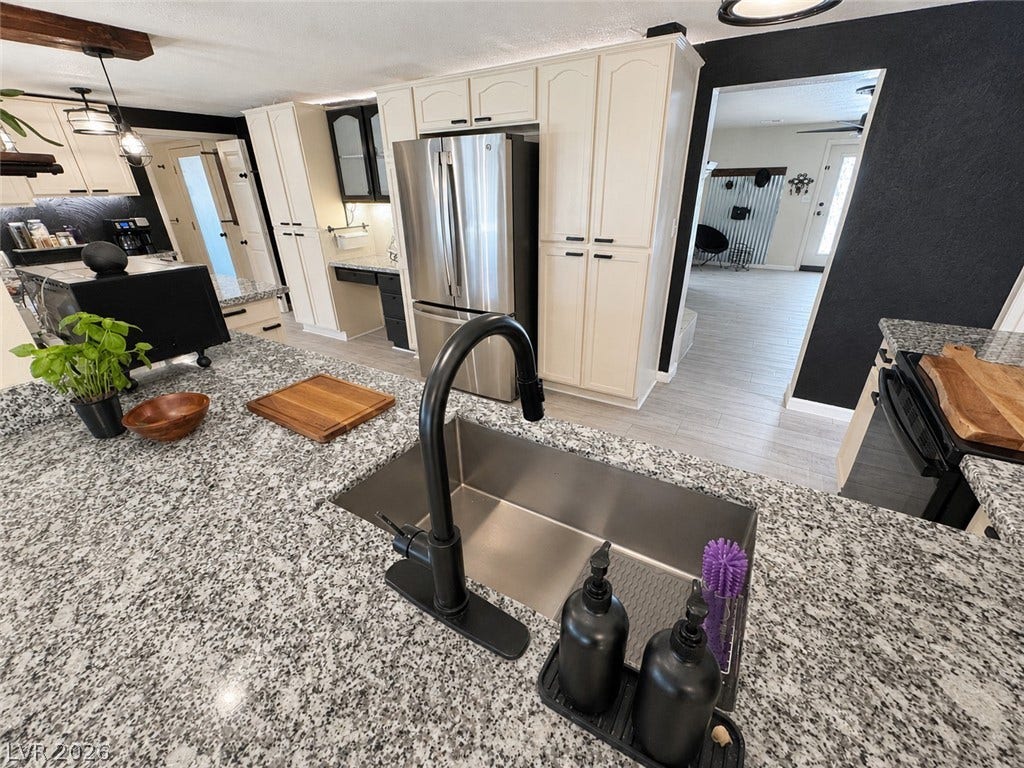 6130 Hawkins Way, Pahrump, NV 89061 An open kitchen layout showcases textured stone countertops and modern stainless steel appliances.