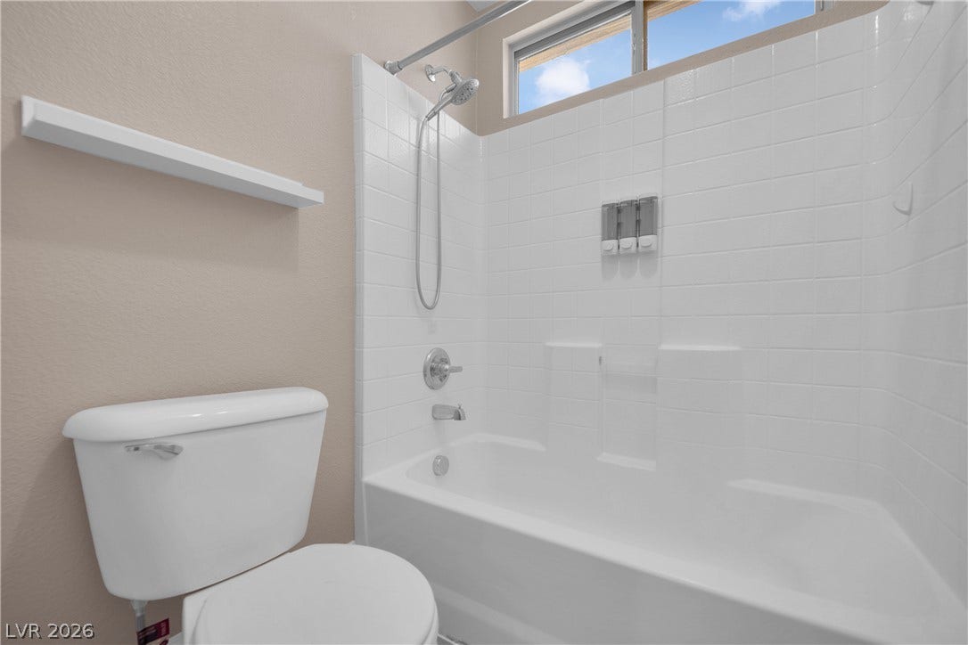 10149 Whitney Falls Court, Las Vegas, NV 89148 White subway tile surrounds the built-in bathtub beneath a high window.
