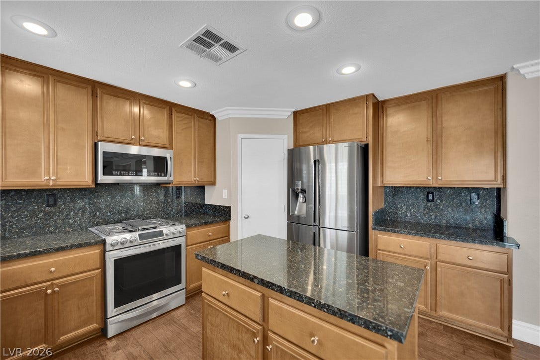 10149 Whitney Falls Court, Las Vegas, NV 89148 Rich wood cabinetry and polished stone countertops elevate this kitchen design.