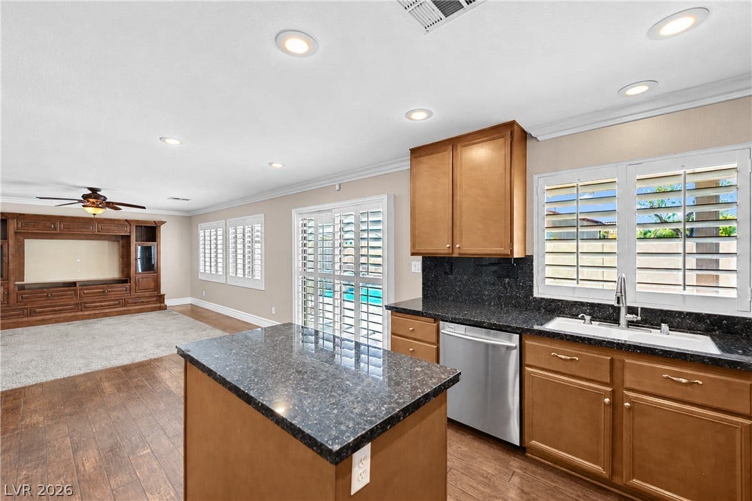 10149 Whitney Falls Court, Las Vegas, NV 89148 Rich wood cabinetry and dark stone countertops anchor this open culinary and living space.