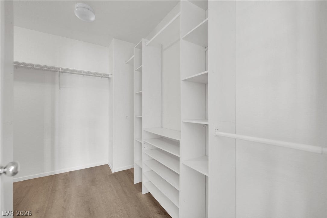 10149 Whitney Falls Court, Las Vegas, NV 89148 A spacious walk-in closet boasts extensive custom shelving and wood-toned flooring.