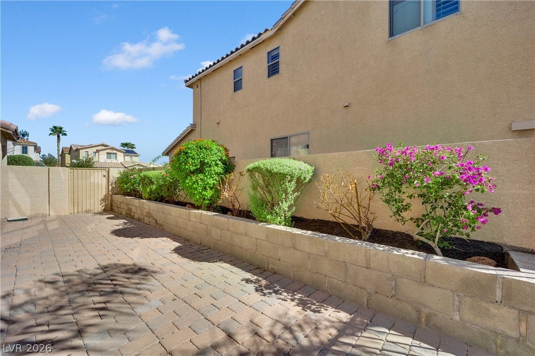 10149 Whitney Falls Court, Las Vegas, NV 89148 An inviting paved patio area showcases structured raised garden beds alongside high stucco privacy walls.