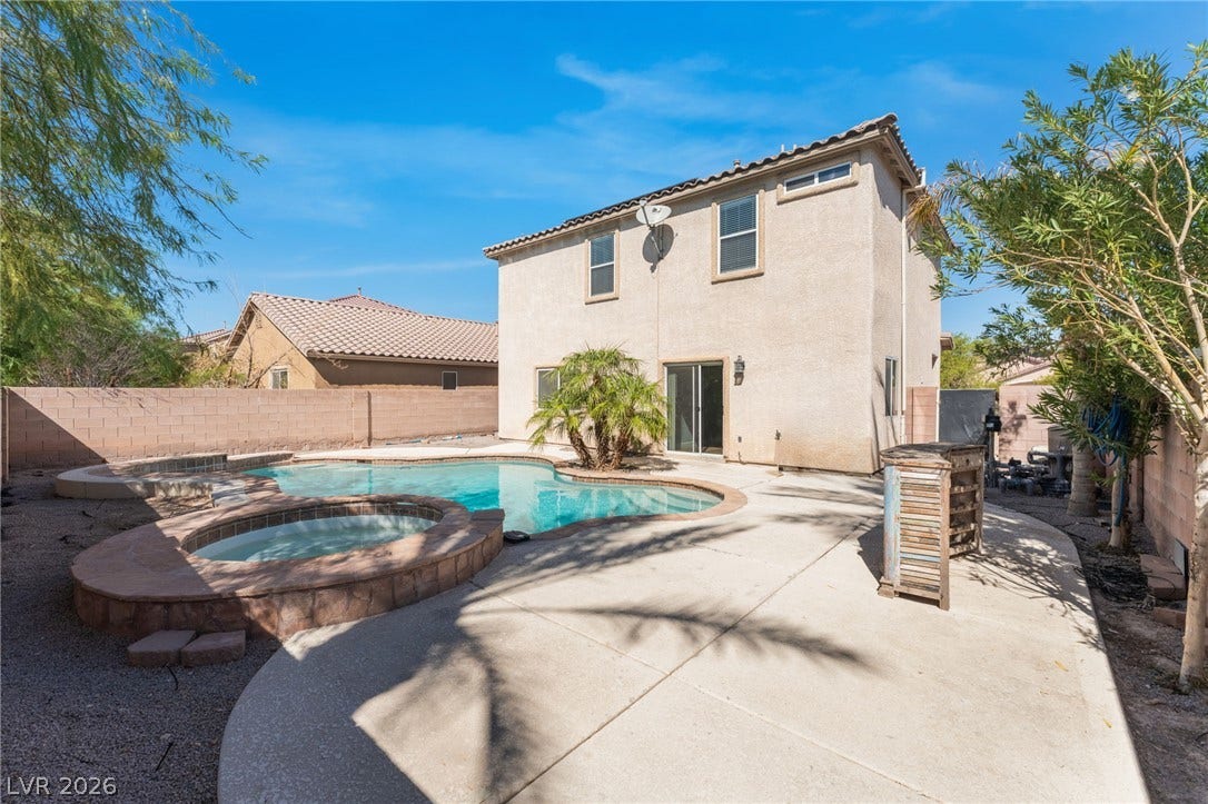 2825 Woodland Park Avenue, North Las Vegas, NV 89086 An inviting backyard oasis features a curved swimming pool and matching spa alongside concrete decking.
