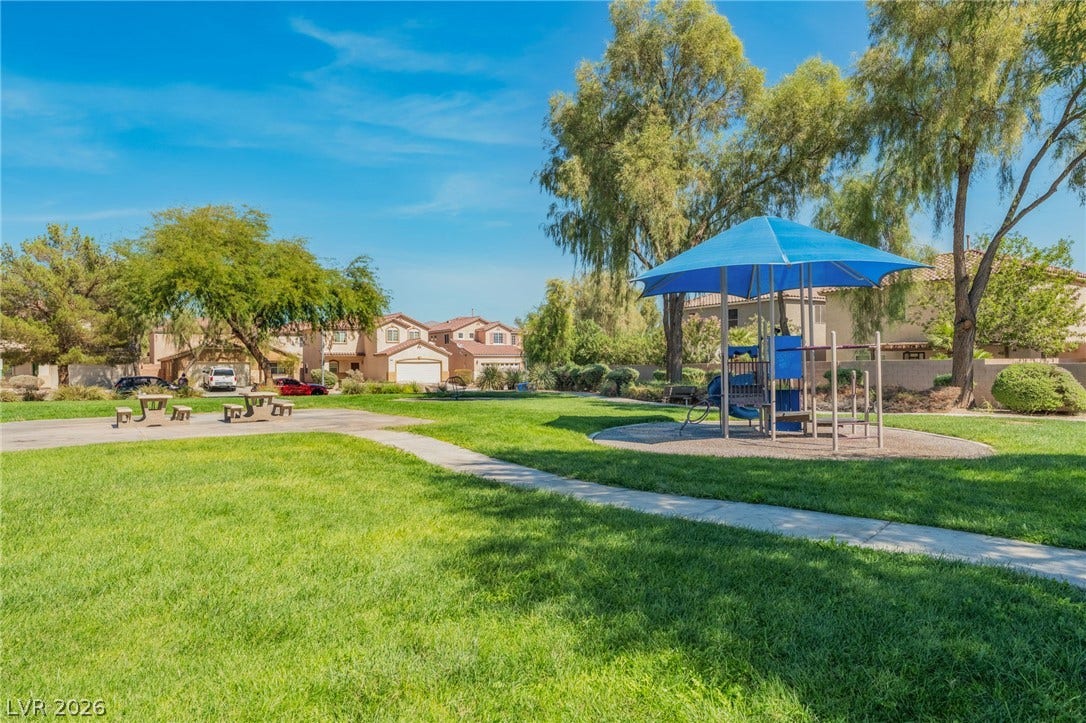 2825 Woodland Park Avenue, North Las Vegas, NV 89086 Mature trees shade a welcoming neighborhood park featuring manicured lawns and a children's play structure.