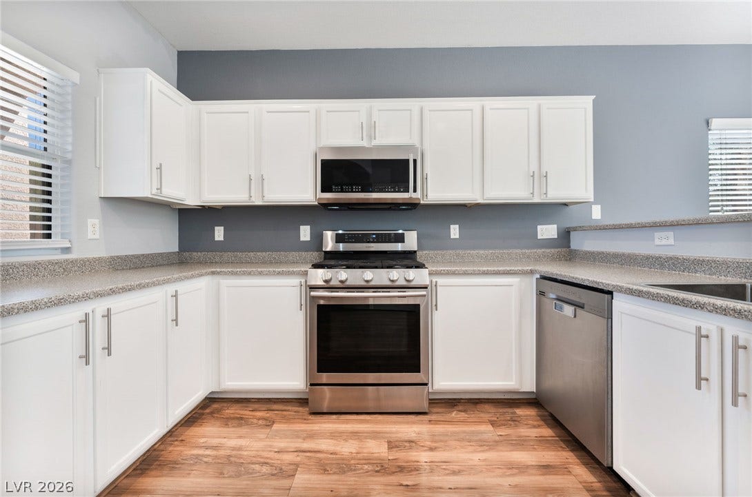 2825 Woodland Park Avenue, North Las Vegas, NV 89086 Crisp white cabinetry contrasts with warm wood-look floors in this functional cooking space.
