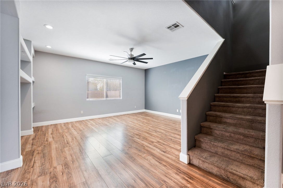 2825 Woodland Park Avenue, North Las Vegas, NV 89086 Rich wood-inspired floors and recessed lighting enhance this versatile living area beside the staircase.