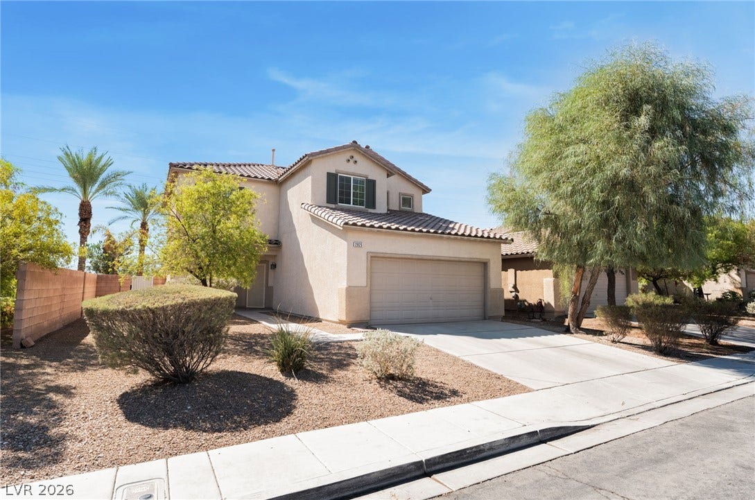 2825 Woodland Park Avenue, North Las Vegas, NV 89086 A two-story stucco exterior stands behind drought-tolerant landscaping and a concrete driveway.
