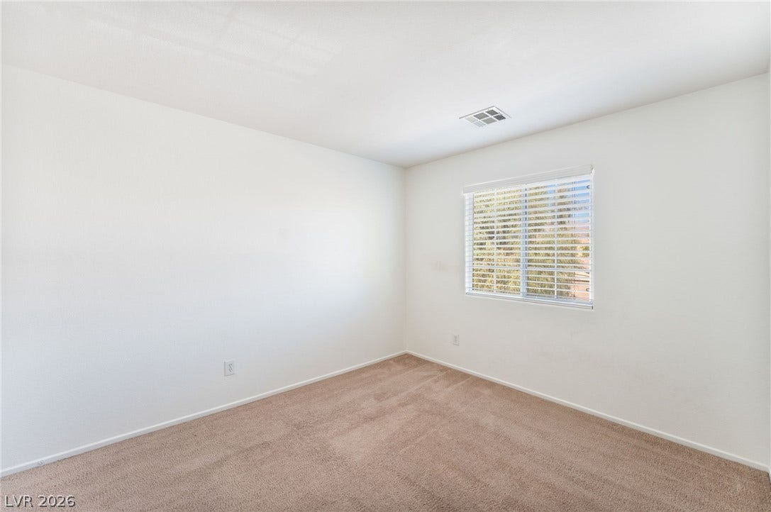 2825 Woodland Park Avenue, North Las Vegas, NV 89086 Plush carpeting and a single window with blinds anchor this minimalist space.