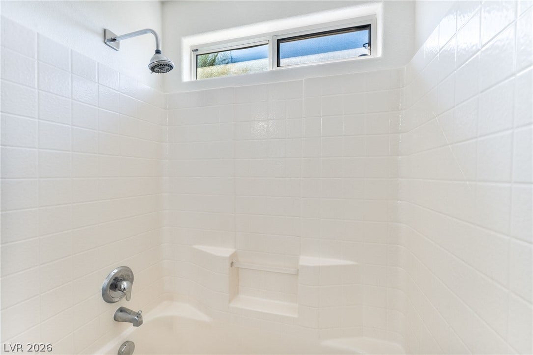 2825 Woodland Park Avenue, North Las Vegas, NV 89086 Crisp tiled walls and a high window define this bright bathtub and shower area.