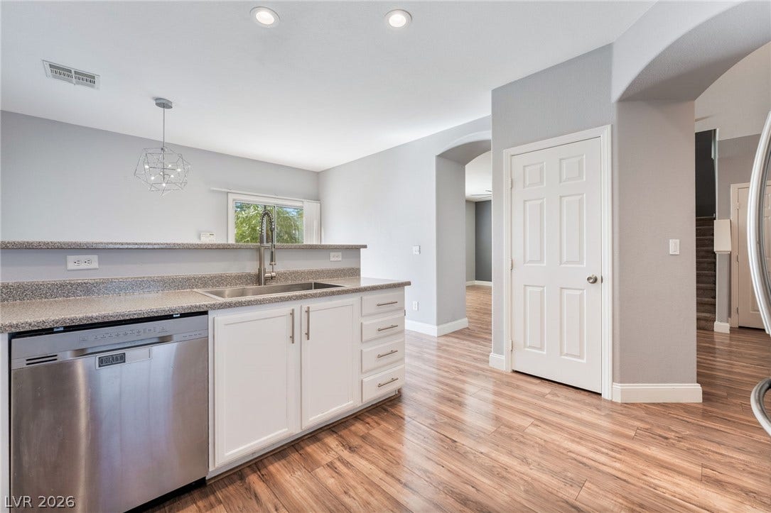 2825 Woodland Park Avenue, North Las Vegas, NV 89086 Rich wood-inspired flooring complements clean white cabinetry in this inviting open-concept layout.