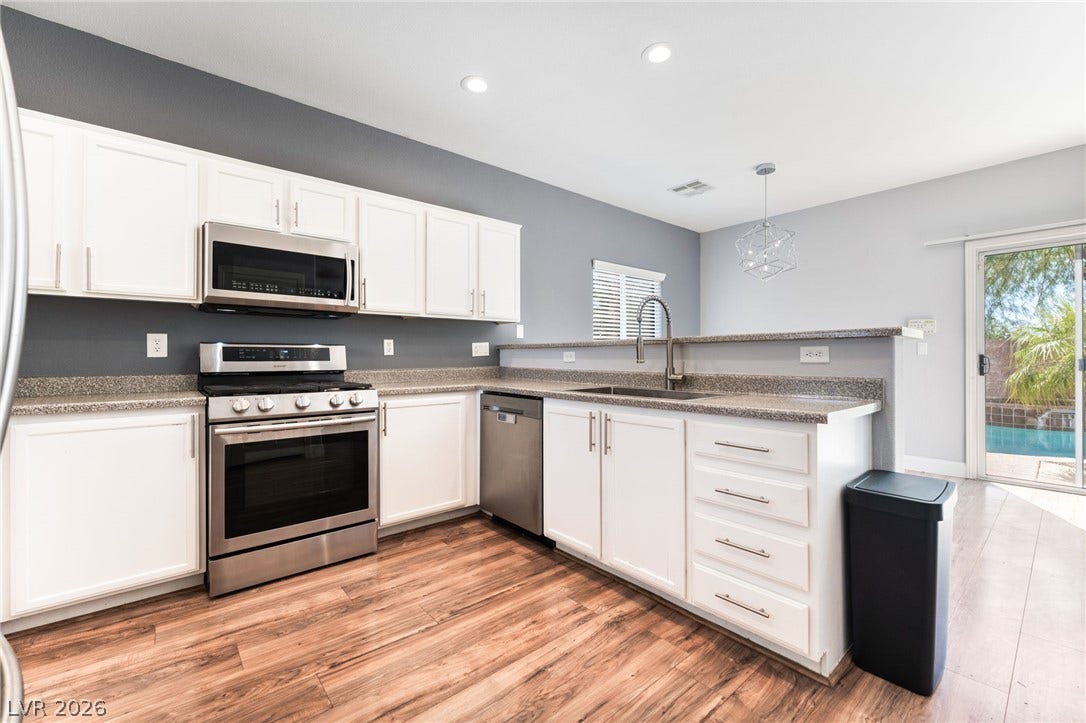2825 Woodland Park Avenue, North Las Vegas, NV 89086 Rich wood flooring pairs beautifully with classic white cabinetry in this bright culinary space.