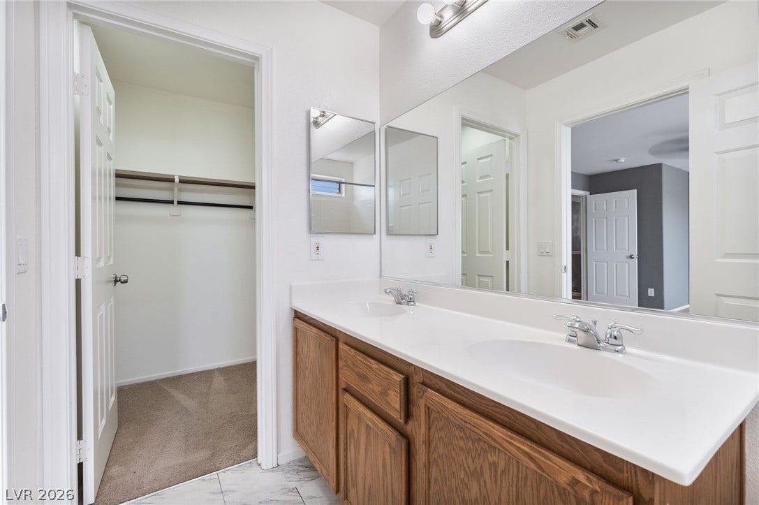 2825 Woodland Park Avenue, North Las Vegas, NV 89086 An adjacent walk-in closet with carpeted flooring supplements this bathroom featuring a dual vanity setup.