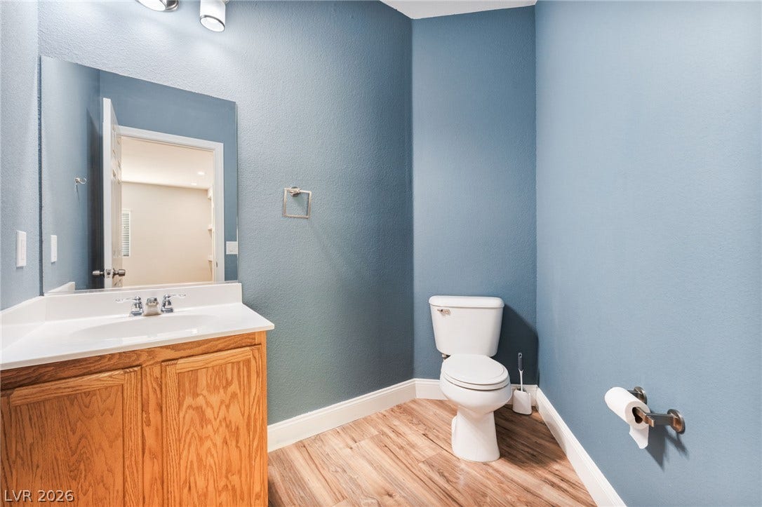 2825 Woodland Park Avenue, North Las Vegas, NV 89086 Rich wood cabinetry and clean stone surfaces anchor this classic powder room.