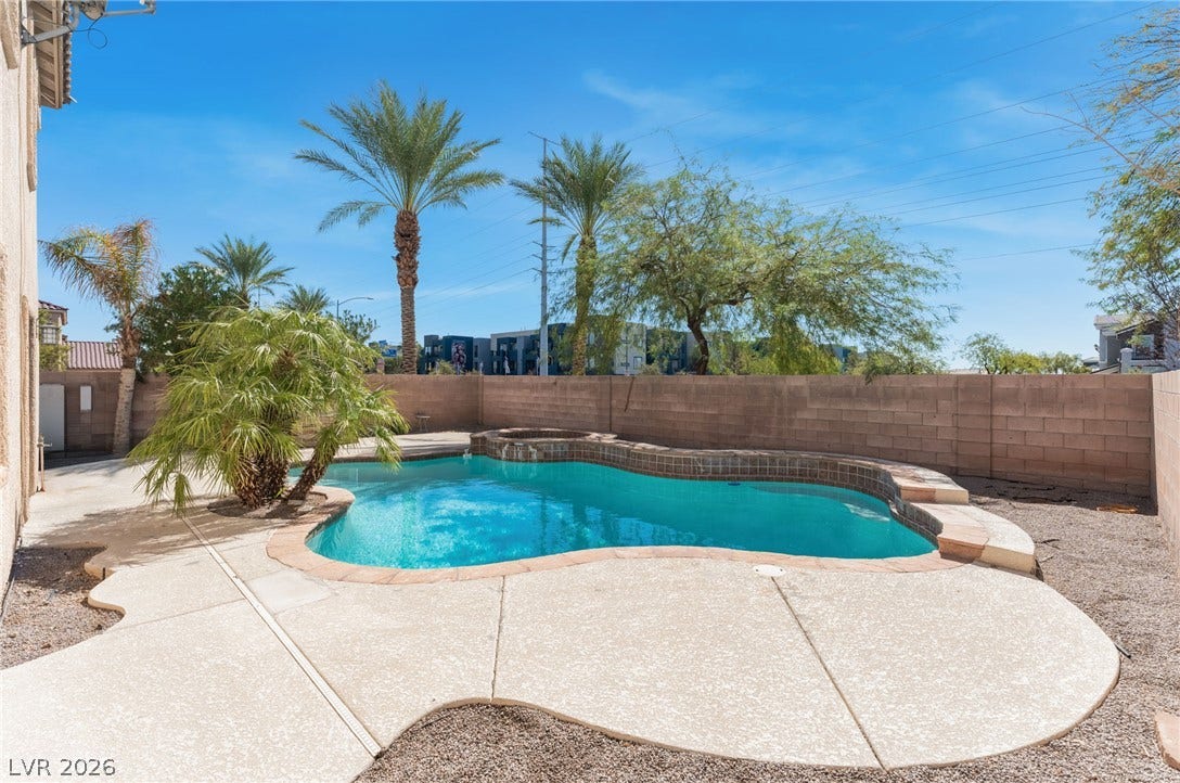 2825 Woodland Park Avenue, North Las Vegas, NV 89086 A sparkling freeform swimming pool anchors this private backyard retreat framed by towering palm trees.