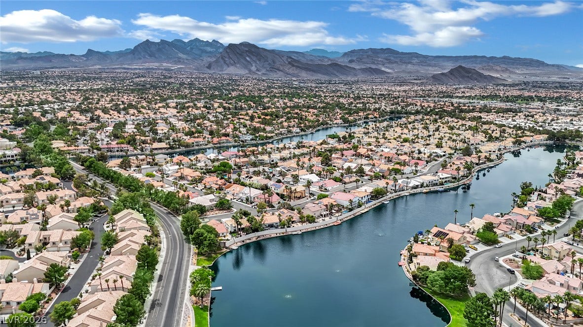 Dramatic mountain vistas rise above a tranquil, winding lake in this peaceful neighborhood setting.