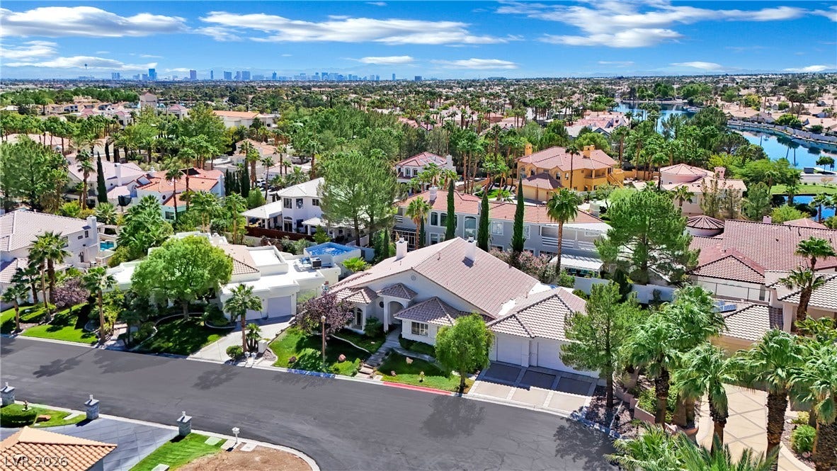 An aerial perspective reveals a serene neighborhood layout complete with red-tile roofs and distant city views.